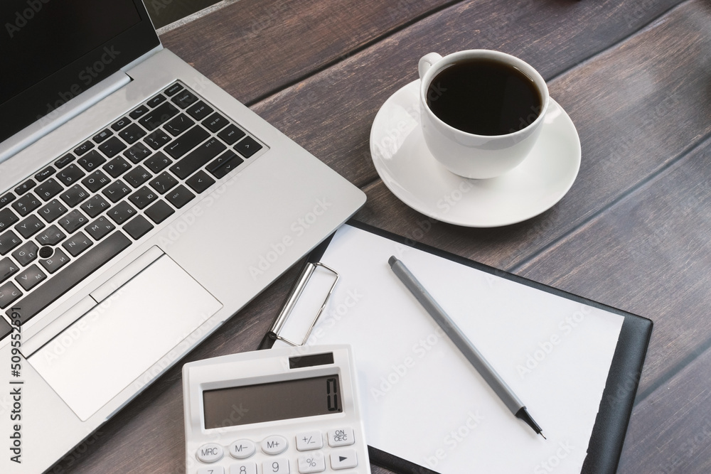 A laptop computer and a cup of coffee. A calculator with the number zero and a notepad. Business concept and education A laptop computer and a cup of coffee. A calculator with the number zero and a notepad. Business concept and education