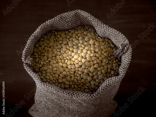 Dried lentils in a sack against a dark background