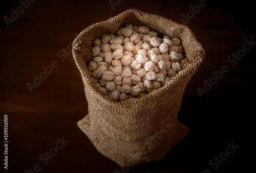 Dried chickpeas in a sack against dark background
