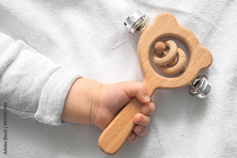 Baby hand holding wooden rattle on white background. Concept of baby wooden toys.  - obrazy, fototapety, plakaty 