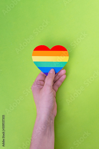 Woman holds in hands a heart in the colors of the rainbow. Pride Month. LGBTIQ+ flag. Love, human rights, tolerance. photo