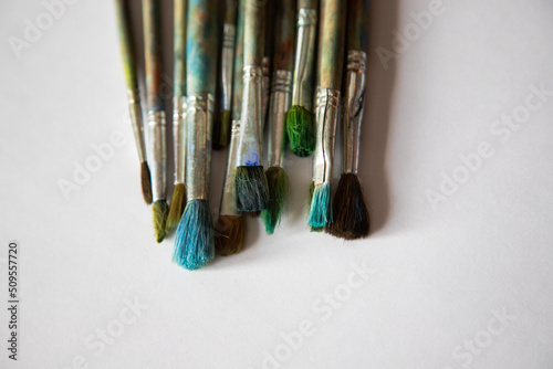 old worn brushes on white paper are folded in a row for drawing, a blank for a designer