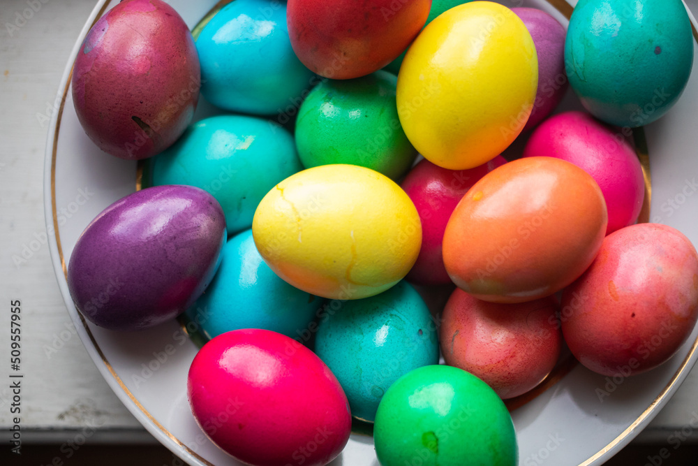 painted multi-colored chicken eggs in a wide white plate as a symbol of the holiday of Catholic believers painted multi-colored chicken eggs in a wide white plate as a symbol of the holiday of Catholic believers