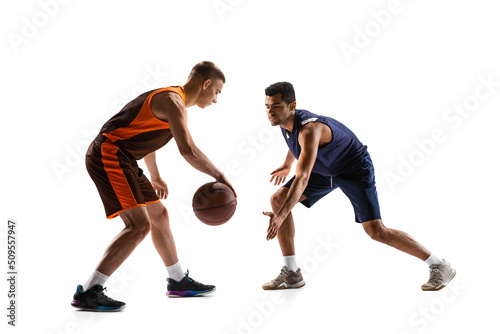 Dynamic portrait of two men, professional basketball player training isolated over white studio background. Dribbling © Lustre