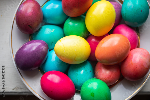 Foto painted multi-colored chicken eggs in a wide white plate as a symbol of the holi