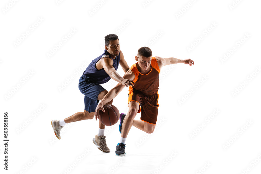 Portrait of two basketball players in motion, training, playing isolated over white studio background. Carrying ball