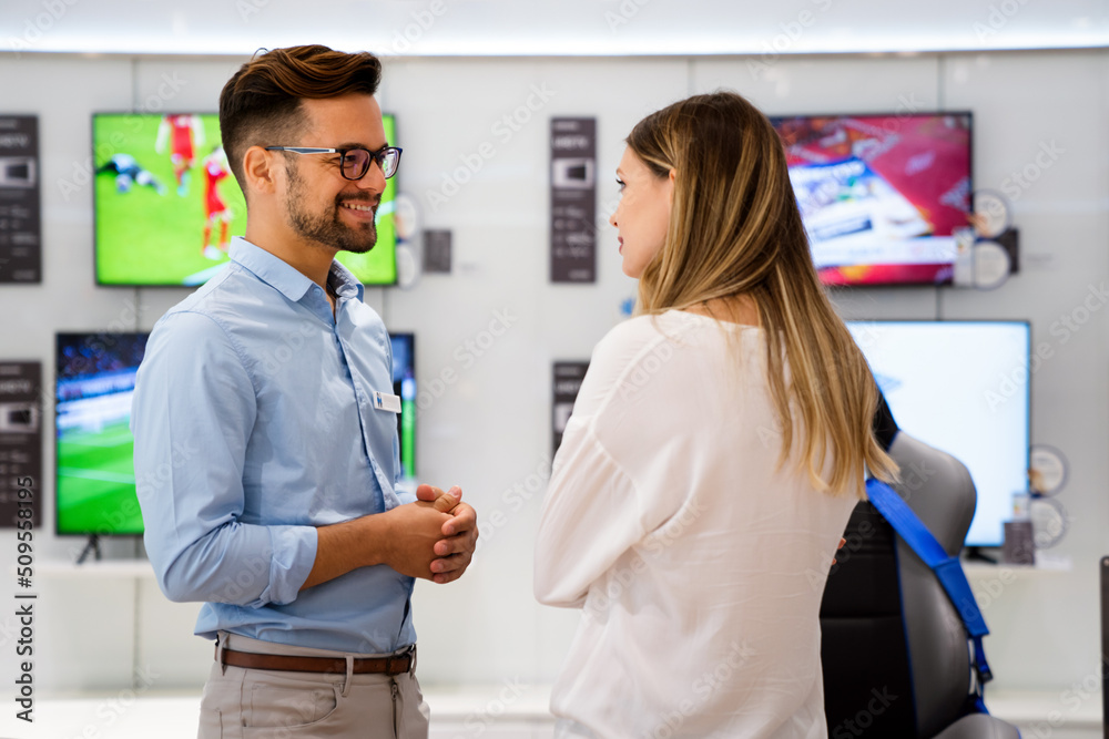 Portrait of salesman helping to woman to buy a new digital device in tech shop