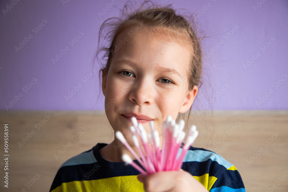 girl child in a striped turtleneck shows cotton swabs for ears girl child in a striped turtleneck shows cotton swabs for ears