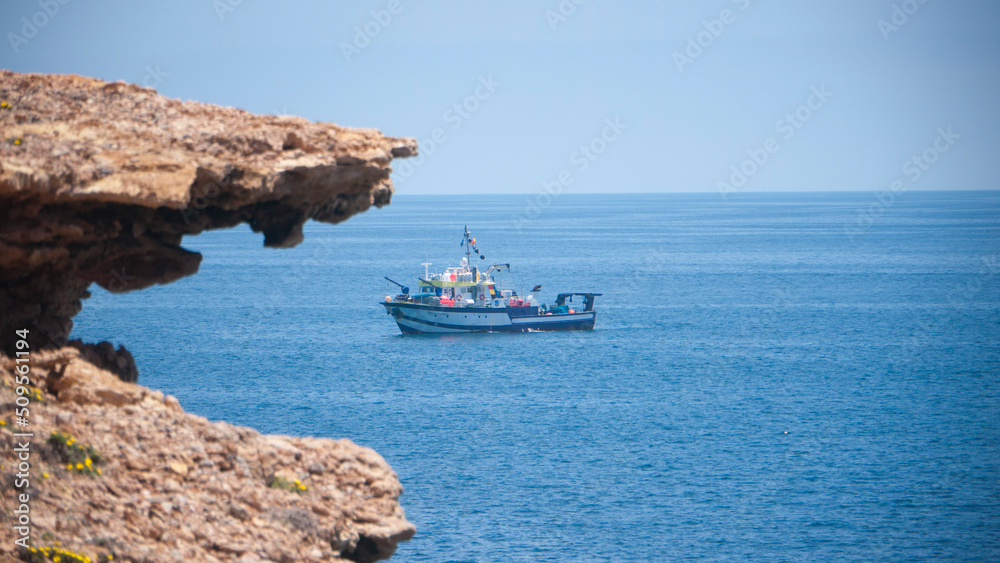 Barco pesquero navegando en mar cerca de litoral rocoso