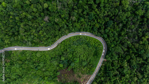 Aerial top view of the the road, Aerial view tropical rain forest with asphalt road cutting through, Road through the green forest Ecosystem and healthy environment background.