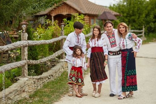 Happy family with kids in traditional romanian dress in a countryside, park. Father, mother, son and daughters walking outside.