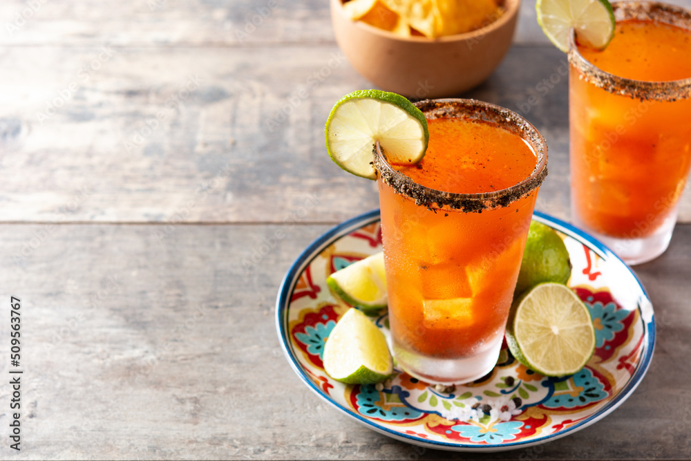 Homemade michelada cocktail with beer, lime juice,hot sauce,salted rim and tomato juice on wooden table. opy space Homemade michelada cocktail with beer, lime juice,hot sauce,salted rim and tomato juice on wooden table. opy space