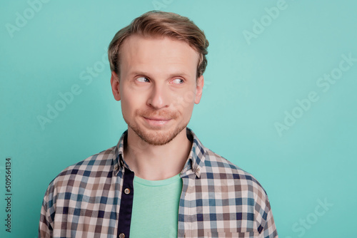Photo of curious thoughtful man look side empty space think dream wear checkered shirt on teal color background © Tetiana