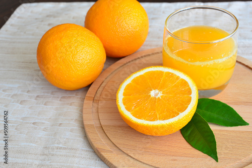 fresh oranges with glass of orange juice on pastel background, close-up