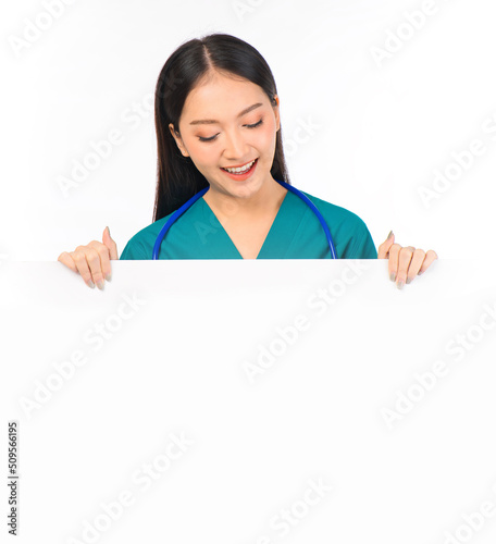 Portrait of professional confident young asian female smiling doctor in green scrubs showing presenting finger to paper billboard, doctor healthcare and doctors concept.