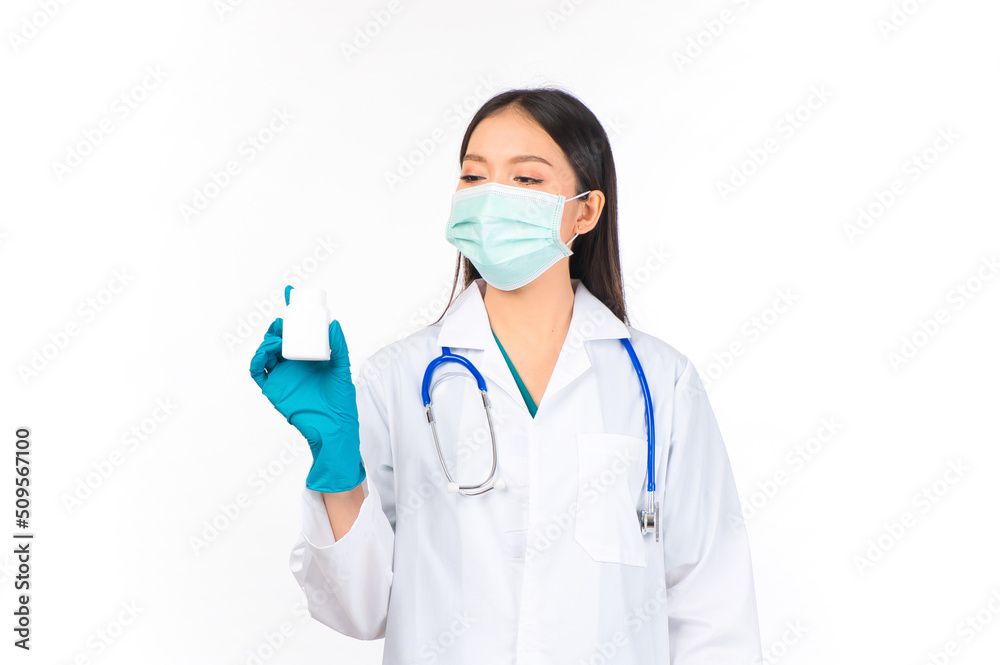 portrait asian female doctor with stethoscope in uniform protection facial mask wearing surgical gloves holding a white pill bottle doctor healthcare and doctors concept. portrait asian female doctor with stethoscope in uniform protection facial mask wearing surgical gloves holding a white pill bottle doctor healthcare and doctors concept.