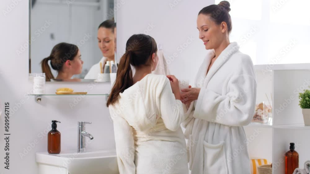 beauty, hygiene and people concept - happy smiling mother and daughter cleaning ears with cotton swabs in bathroom beauty, hygiene and people concept - happy smiling mother and daughter cleaning ears with cotton swabs in bathroom