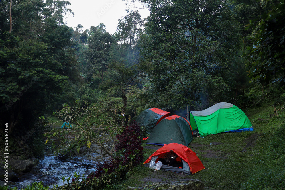 Group of camping tents beside the small river on the forest.