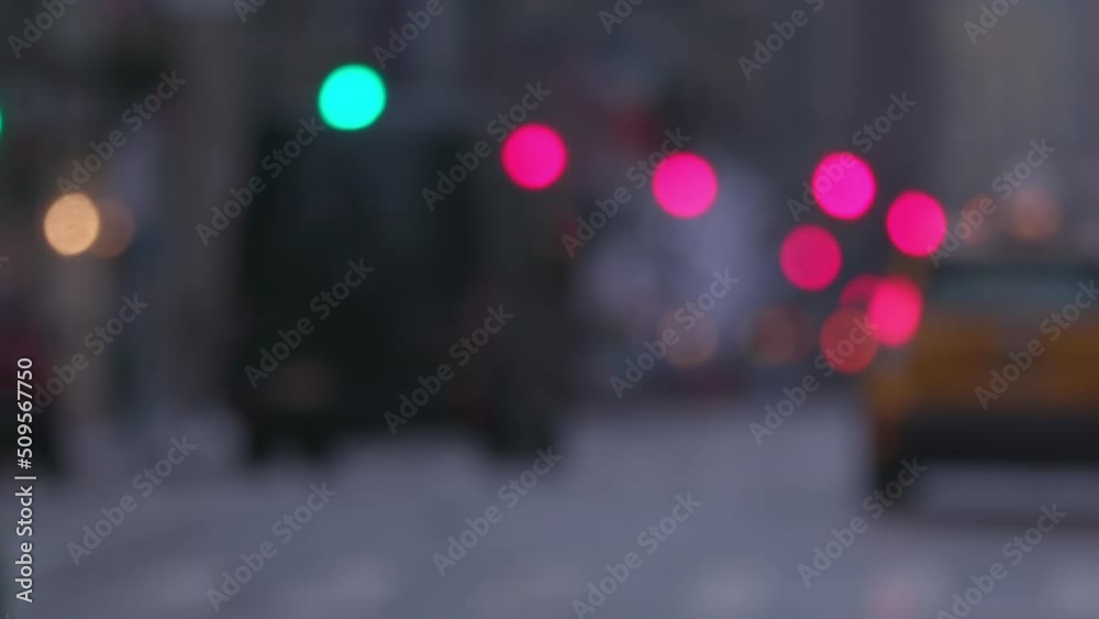 Blurred slow-mo of a wet New York Manhattan main street with traffic, yellow taxi, out of focus lights.