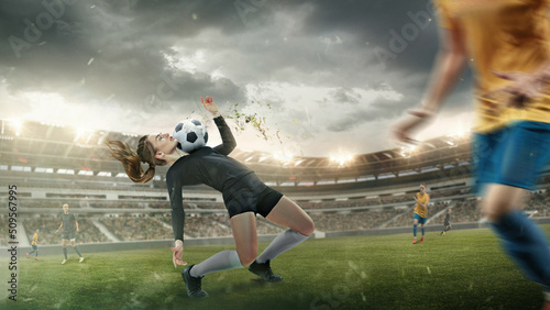 Young female soccer or football players in sportwear kicking ball for the goal in action at the stadium. Concept of healthy lifestyle, sport, motion, movement. © master1305