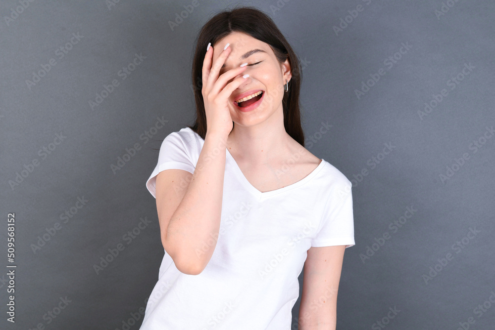 Charismatic carefree joyful young beautiful Caucasian woman wearing white T-shirt over studio grey wall likes laugh out loud not hiding emotions giggling hear funny hilarious joke chuckling facepalm. Charismatic carefree joyful young beautiful Caucasian woman wearing white T-shirt over studio grey wall likes laugh out loud not hiding emotions giggling hear funny hilarious joke chuckling facepalm.