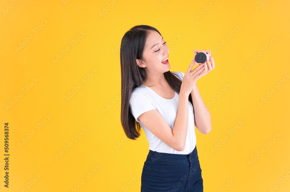Photo cute pretty asian woman smile showing easy to keep money in piggy bank, Business and money and financial concepts yellow background. Photo cute pretty asian woman smile showing easy to keep money in piggy bank, Business and money and financial concepts yellow background.