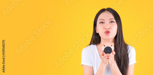 Photo cute pretty asian woman smile showing easy to keep money in piggy bank, Business and money and financial concepts yellow background.