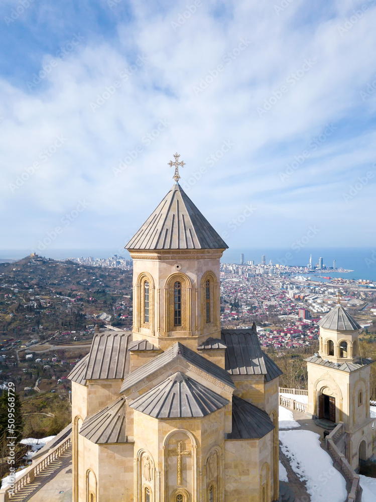 View from the don to the Church of the Holy Trinity on Mount Sameba in Batumi, Adjara, Georgia on a sunny day with remnants of snow, city and sea views. Vertical photo