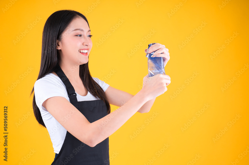 attractive asian female smile wearing apron pointing fingers to plastic bottle in a garbage bag for Recycling, world environment day. attractive asian female smile wearing apron pointing fingers to plastic bottle in a garbage bag for Recycling, world environment day.