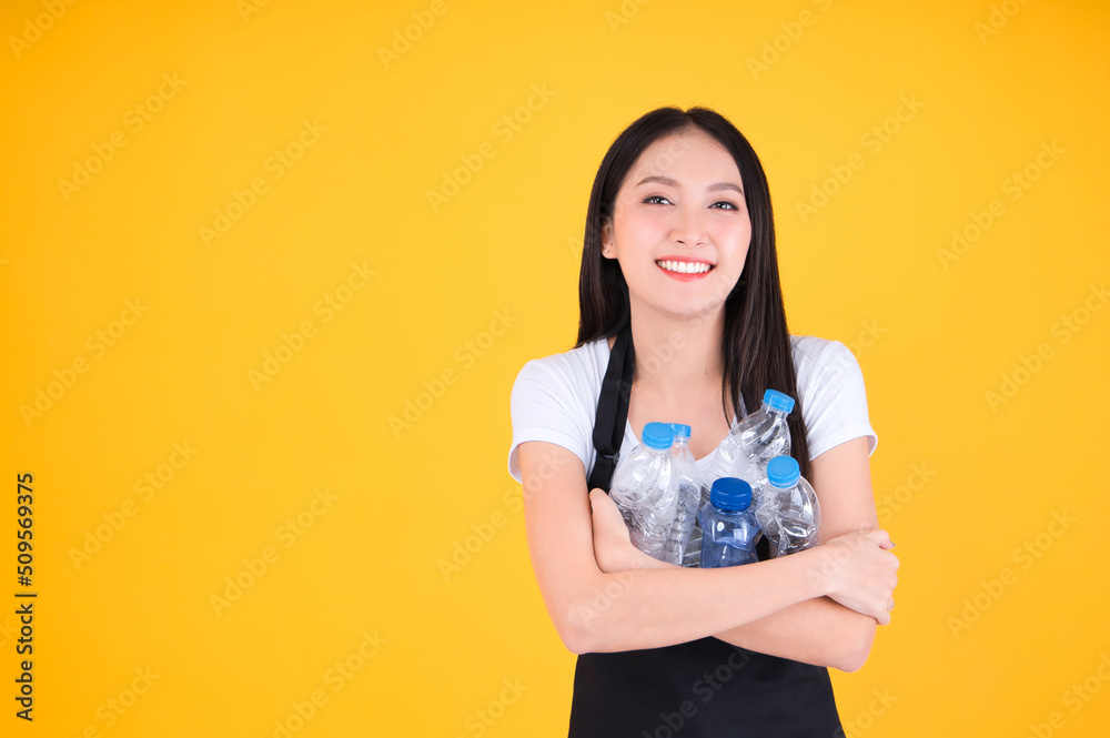 attractive asian female beautiful smile wearing apron pointing fingers to plastic bottle in a garbage bag for Recycling, world environment day. attractive asian female beautiful smile wearing apron pointing fingers to plastic bottle in a garbage bag for Recycling, world environment day.