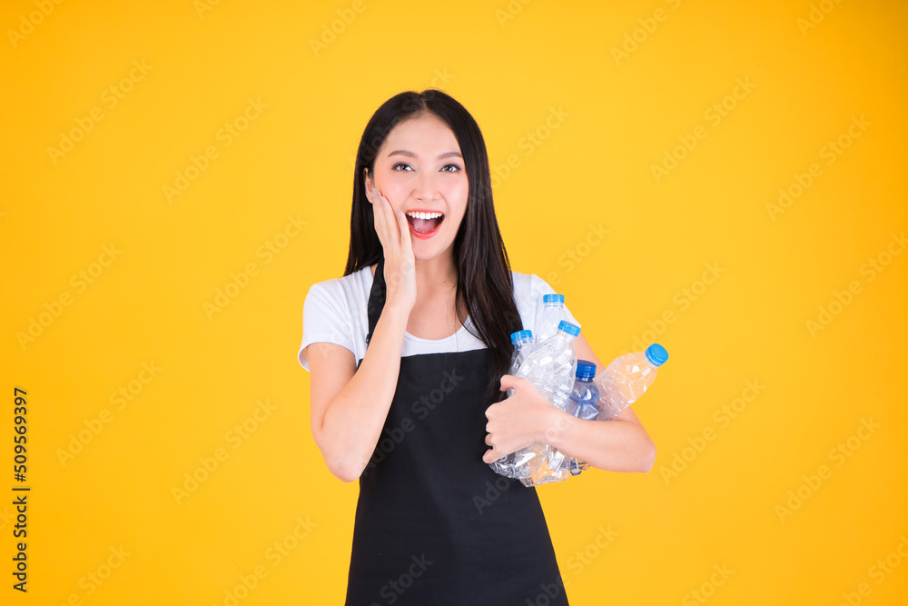 attractive asian female smile wearing  apron pointing fingers to plastic bottle in a garbage bag for Recycling, world environment day.