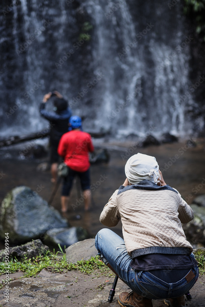Back side of group landscape photographers capturing small waterfall. Back side of group landscape photographers capturing small waterfall.