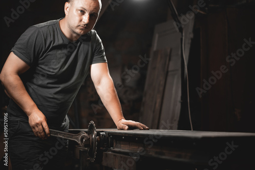 A man works with a large wrench in his home workshop. Making metal products with your own hands