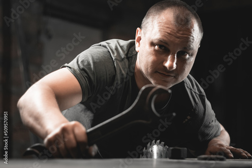 A man works with a large wrench in his home workshop. Making metal products with your own hands