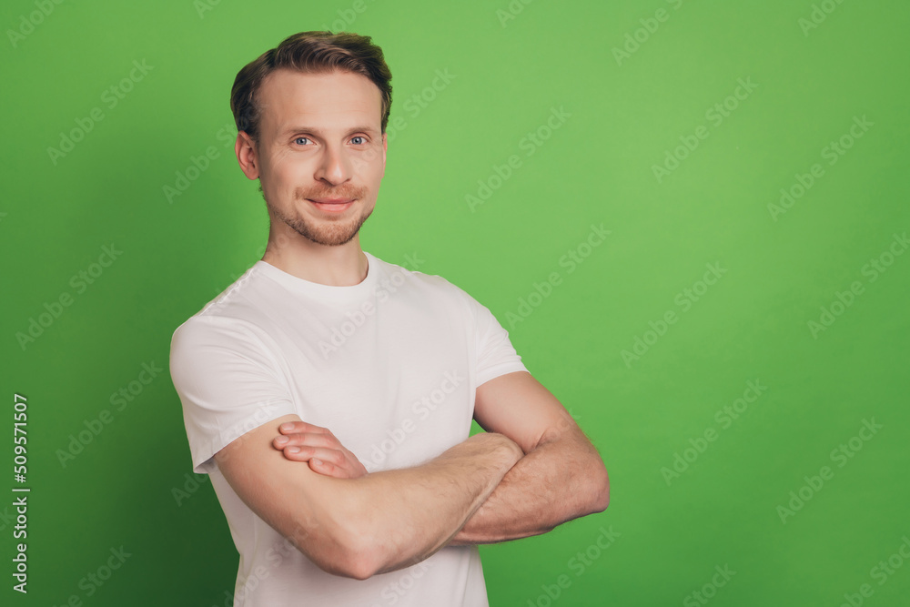 Cheerful positive masculine strong attractive man folded arms isolated on green color background Cheerful positive masculine strong attractive man folded arms isolated on green color background