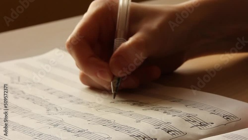 Handwritten notes and female hand holding a pen and writing notes, composing music, selective focus