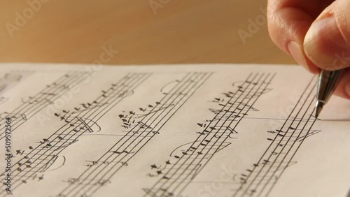 Handwritten notes and female hand holding a pen and writing notes, composing music, selective focus