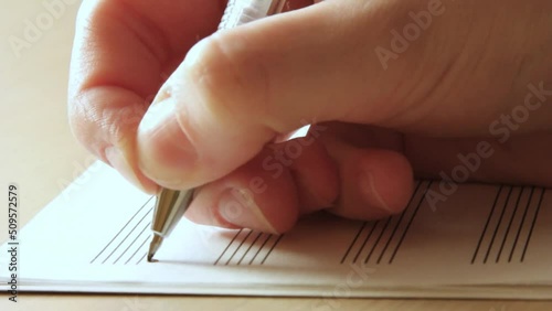 Handwritten notes and female hand holding a pen and writing notes, composing music, selective focus