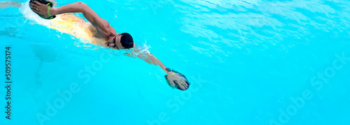Man swimming with crawl in the pool. Triathlon fitness athlete swimming training. Swimmer person floating in turquoise water banner panorama. Sports and fitness cardio exercises. Panorama banner.