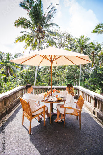 Fototapeta Naklejka Na Ścianę i Meble -  Young Couple Having Breakfast On The Terrace With The Jungle View In Bali, Indonesia