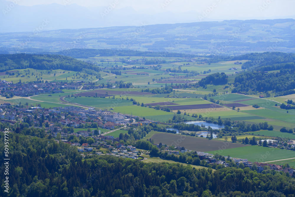 Fototapeta premium Aerial view of midland with agricultural fields, wood, ponds and hills seen from local mountain Uetliberg on a sunny spring day. Photo taken May 18th, 2022, Zurich, Switzerland.
