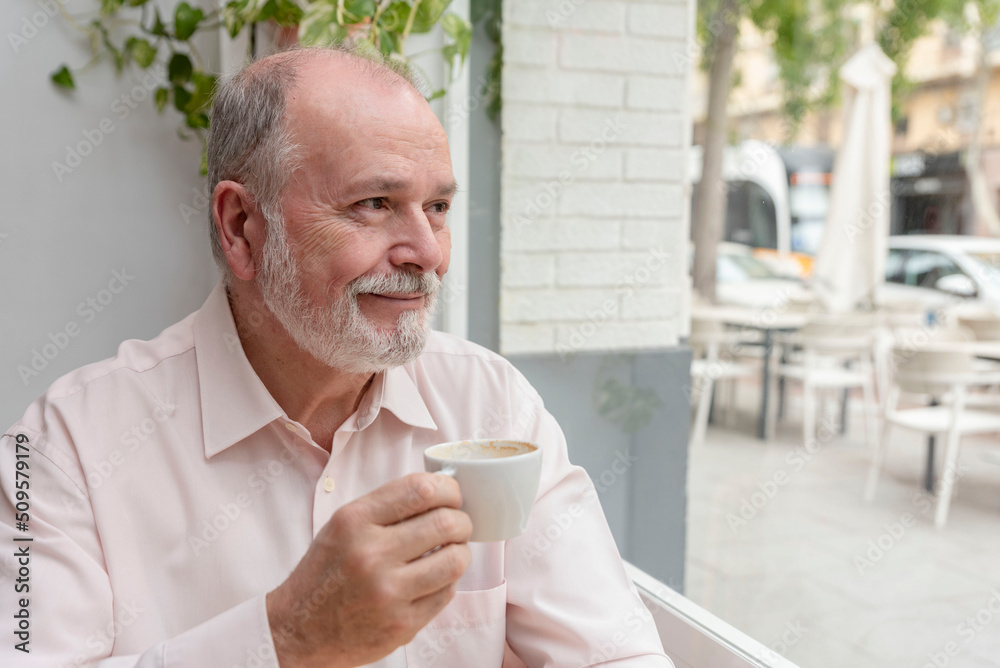 portrait of a smiling elder man looking out of the window enjoying a cup of coffee portrait of a smiling elder man looking out of the window enjoying a cup of coffee
