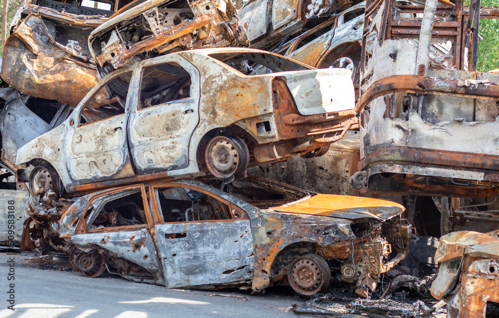 A view of burnt-out cars after rocket attacks by the Russian military. War of Russia against Ukraine. Civil vehicle after the fire. Cemetery of cars in the city of Irpin. Rusty pile of metal.