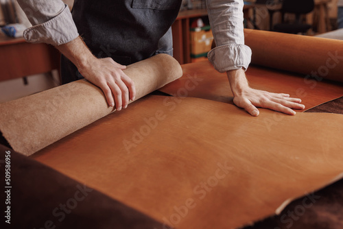 Cobbler working with natural brown leather, top view photo