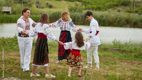 Foto Beautiful couple with their children dressed in traditional costume dancing together national romanian dance
