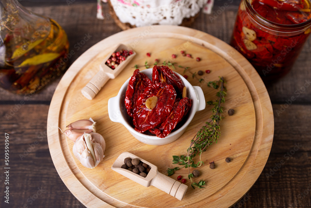 Sun-dried tomatoes in olive oil in a white bowl with pepper, garlic and thyme on a wooden board. Home cooking, rustic style. Selective focus, close-up. Sun-dried tomatoes in olive oil in a white bowl with pepper, garlic and thyme on a wooden board. Home cooking, rustic style. Selective focus, close-up.