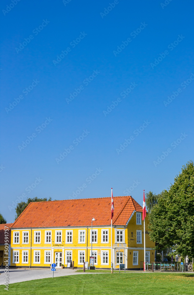Danish flags in front of the colorful yellow house in Jelling, Denmark