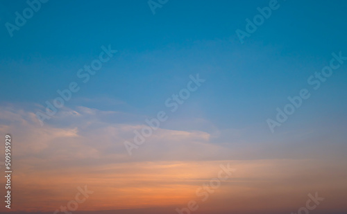 Bright orange sunset sky background with gentle colorful clouds, soft focus