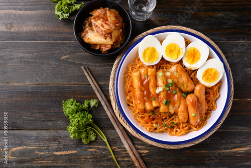 Korean spicy instant noodle with Tteokbokki, sausage and egg on wooden background, Table top view