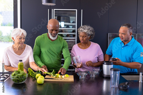 Leinwand Poster Multiracial senior friends making smoothie with granny smith apples and leaf veg